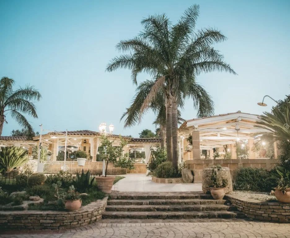 Ingresso illuminato e palme della Villa del Poggio Mulara